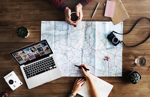 2 people planning with a map surrounded by various gadgets